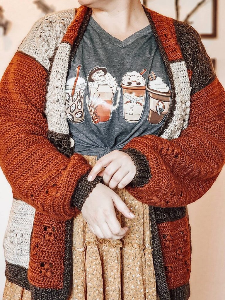 Close-up of a rust, cream and brown Barley crochet cardigan with patchwork textured squares, solid sleeves and ribbed edging.